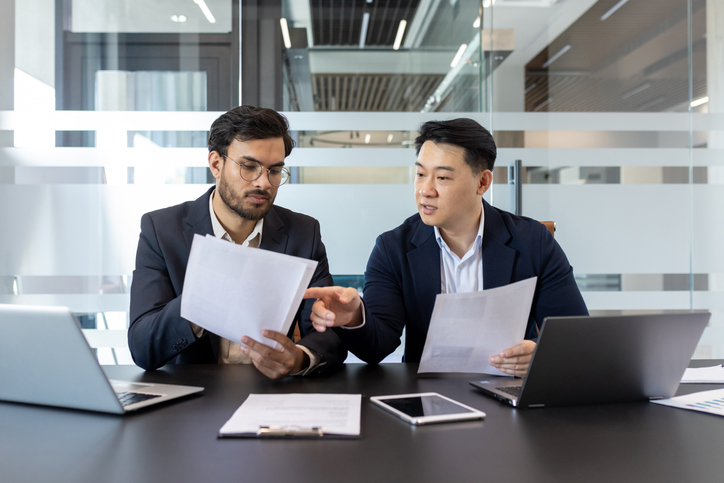 Two professionals reviewing documents and data during a focused internal discussion